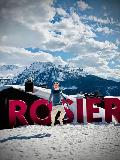 Un jeune saute dans la neige devant les grandes lettres de la station